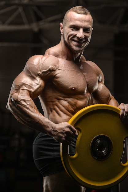 Muscular bodybuilder fitness man doing abs exercises in gym