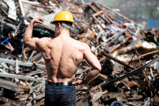 Foto culturista muscolare che flette i muscoli nell'iarda industriale della spazzatura