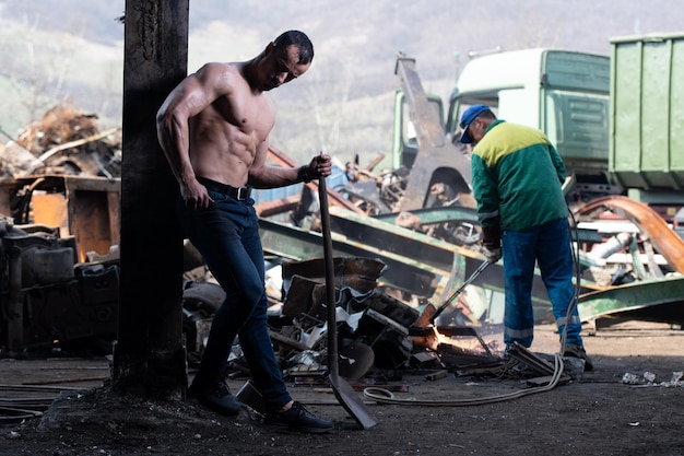 Muscular Bodybuilder Flexing Muscles With Shovel