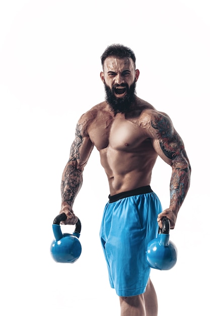 Muscular bodybuilder guy doing exercises with kettlebells