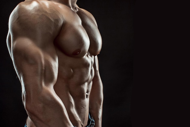 Muscular bodybuilder guy doing posing over black background