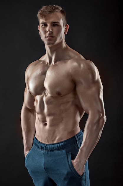 Muscular bodybuilder guy doing posing over black background