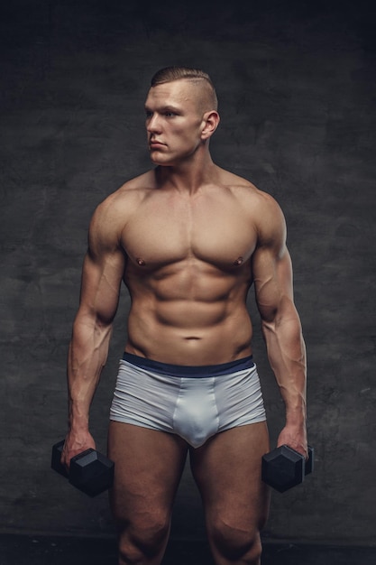 Muscular bodybuilder in a white panties holds a pair of dumbbells.