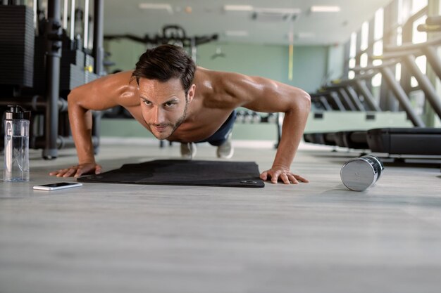 Muscular build man doing pushups in a gym