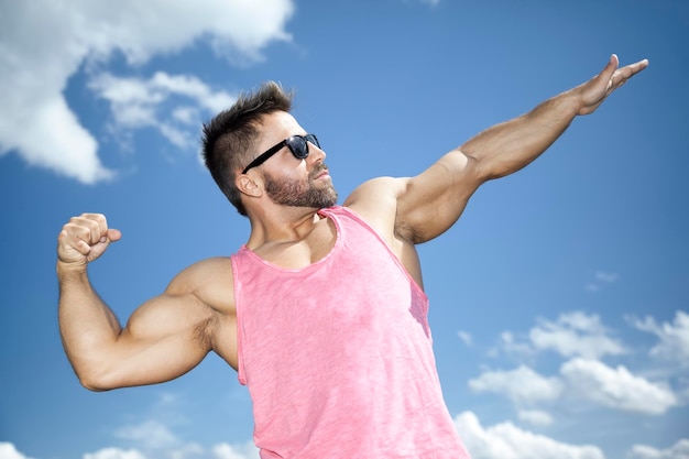 Muscular build man gesturing against sky