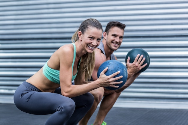 Photo muscular couple doing ball exercise