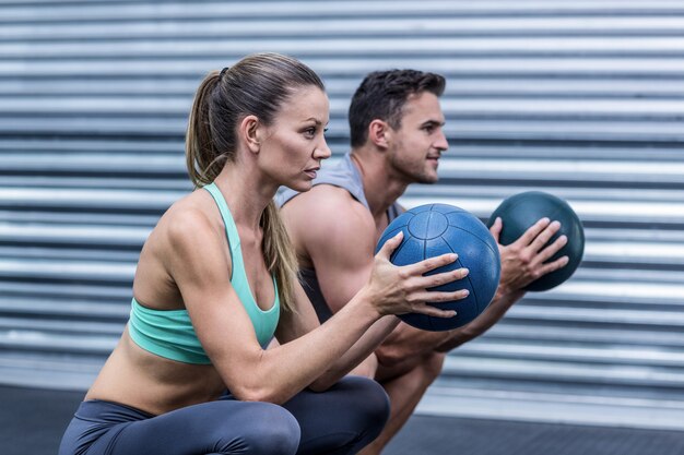 Muscular couple doing ball exercise