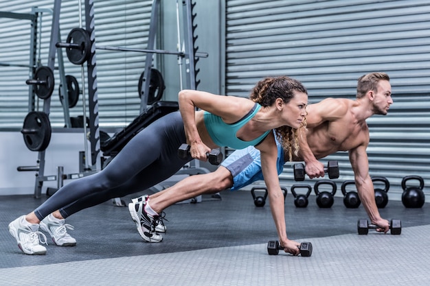 Muscular couple doing plank exercise together