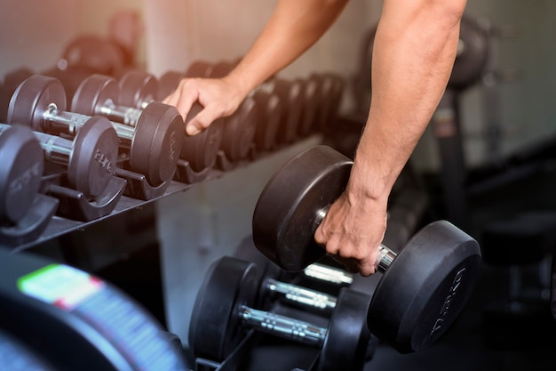 Muscular fitness man bodybuilder is workout with dumbbells in gym