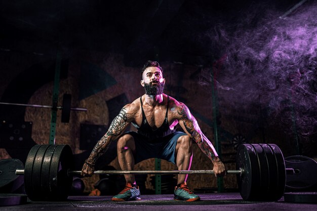 Muscular fitness man doing deadlift of a barbell in modern fitness center. Functional training.