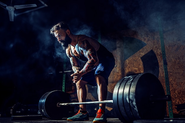 Muscular fitness man preparing to deadlift of a barbell in modern fitness center. Functional training.