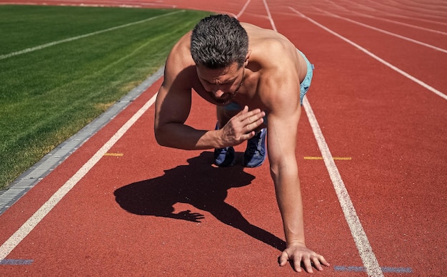 Muscular guy doing pushups standing in plank in outdoor stadium
sport