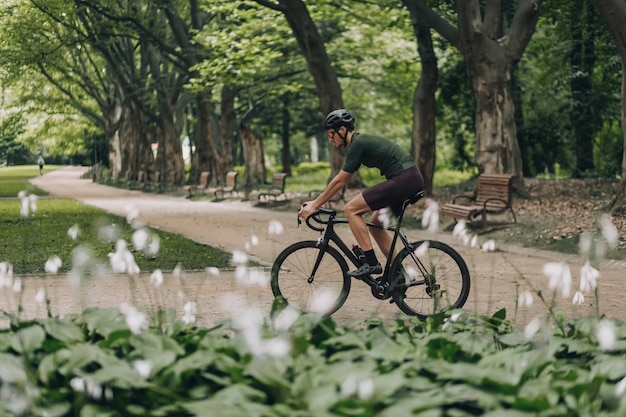 Photo muscular guy enjoying morning cycling at green park