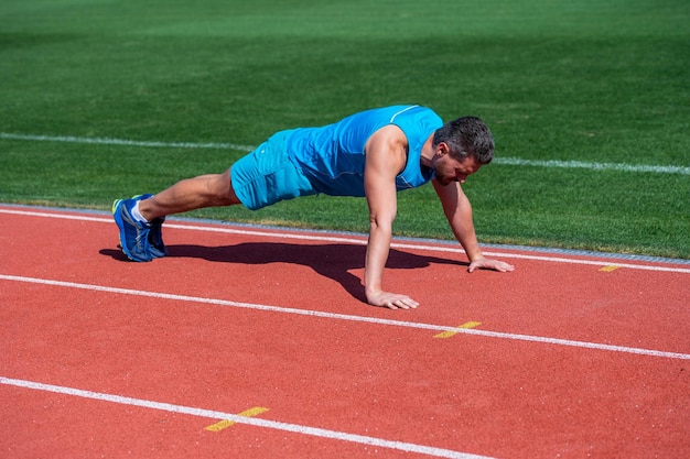 근육 질의 남자는 판자에 서서 스포츠 훈련 운동에 밀어 넣습니다.