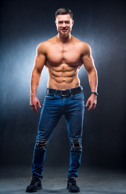 腰に手を当ててポーズをとる裸の胴体を持つ筋肉の男 プレミアム写真