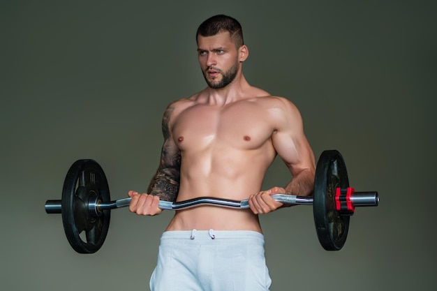 Мускулистый красавчик с позированием в тренажерном зале фитнес-мужская модель рядом с тренажерным залом