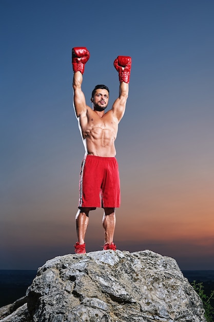 Muscular male boxer posingoutdoors