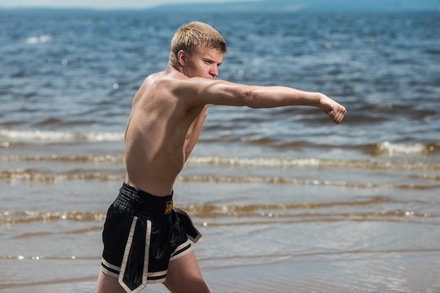 Addestramento muscolare combattente maschio. il pugile si allena all'aria aperta