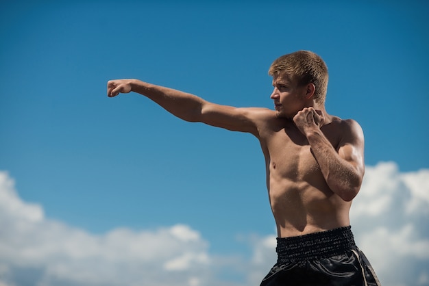 Тренировка мускулистого бойца-мужчины, тренировка боксера на открытом воздухе