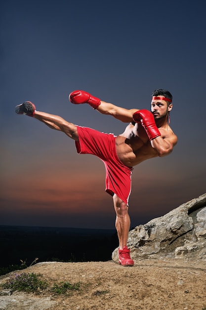 Muscular male kickboxer training outdoors