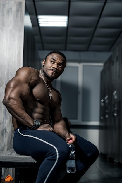 Muscular man african bodybuilder Happy young african man drinking water after exercise