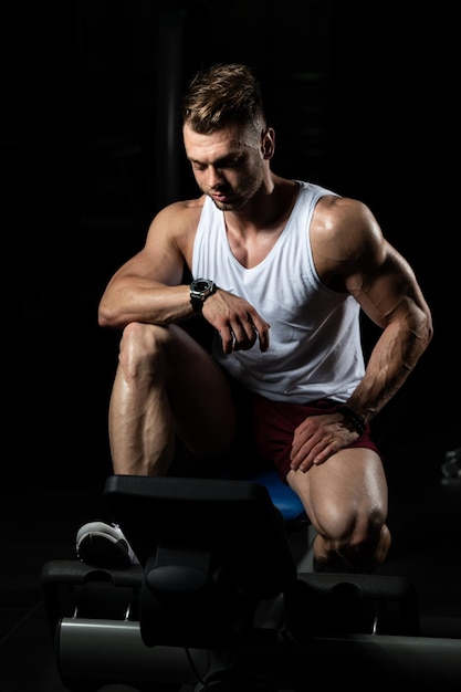 Мускулистый мужчина после тренировки отдыхает в спортзале