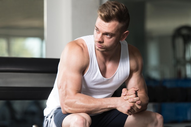 Photo muscular man after exercise resting in gym