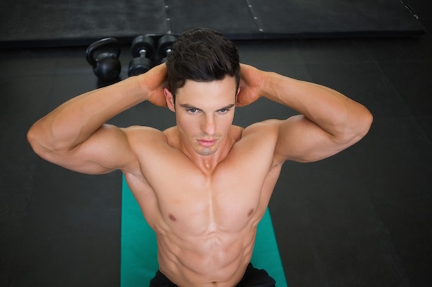 Muscular man doing abdominal crunches in gym