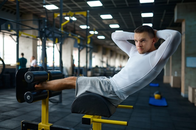 Фото Мускулистый мужчина делает упражнения на пресс, фитнес-тренировки в тренажерном зале
