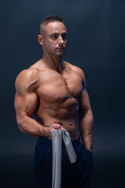 Muscular man doing calisthenic exercise with power band isolated.