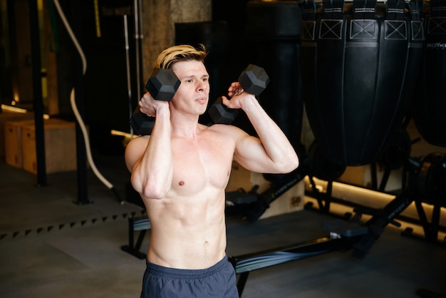 Muscular man doing exercise with dumbbells