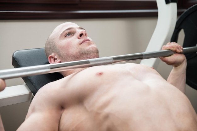 Muscular Man Doing Heavy Weight Exercise For Chest On Bench Press In Gym