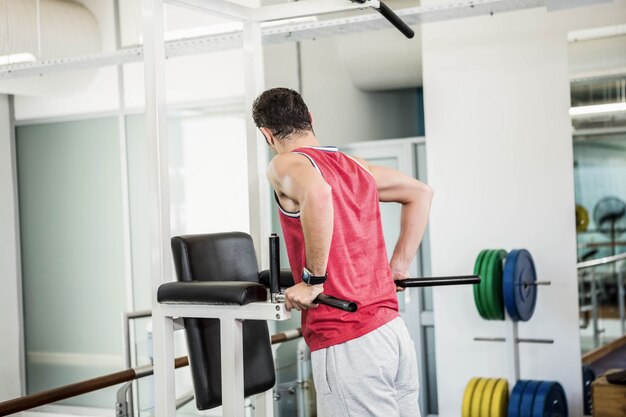 Muscular man doing pull up in a gym