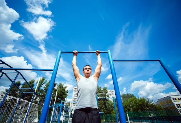 Muscular man doing pull-ups on horizontal bar 