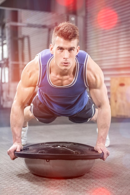 Photo muscular man doing push up on bosu ball at crossfit gym