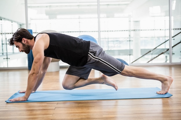 Muscular man doing push up on mat in the studio