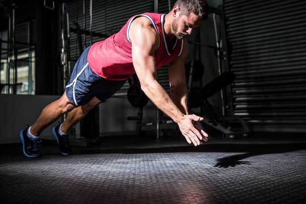 Uomo muscolare facendo flessioni con battito delle mani