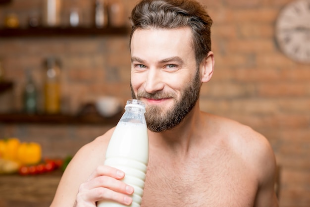 Muscular man drinking milk from the bottle on the kitchen