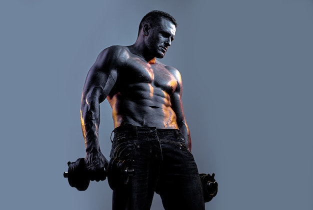 Muscular man exercises with dumbbell over neon black blue background.