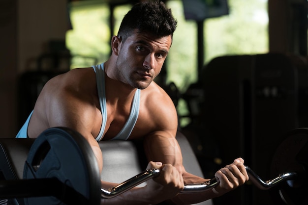 Muscular Man Exercising Biceps With Barbell