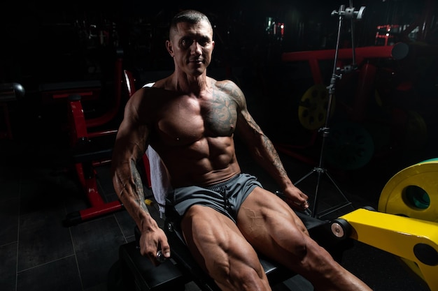 Muscular Man Exercising Quadriceps On Machine