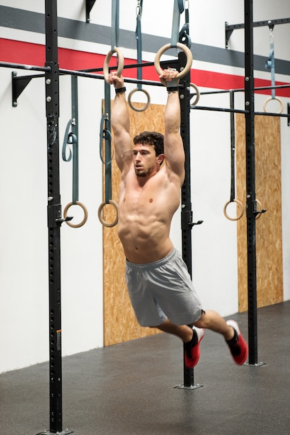 Muscular man exercising on rings