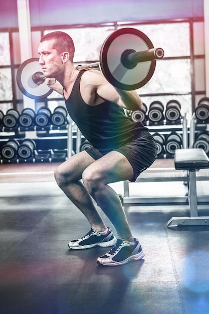 Photo muscular man exercising with barebell at gym