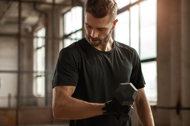 Muscular man exercising with dumbbells in gym