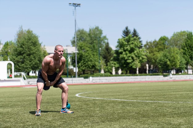 Muscular Man Exercising With Kettlebell Outdoor