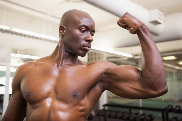 Photo muscular man flexing muscles in gym