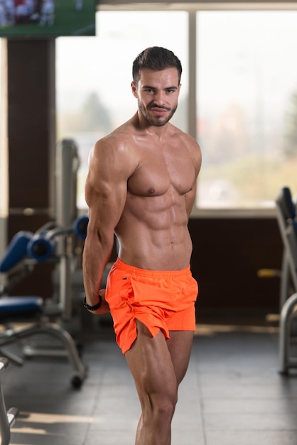 Muscular Man Flexing Muscles In Gym