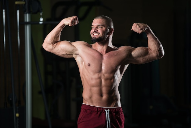 Muscular Man Flexing Muscles In Gym