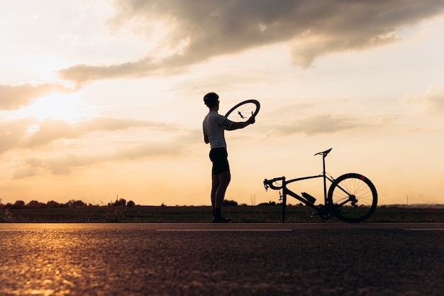 写真 新鮮な壊れた自転車のシルエット固定ホイールの筋肉男