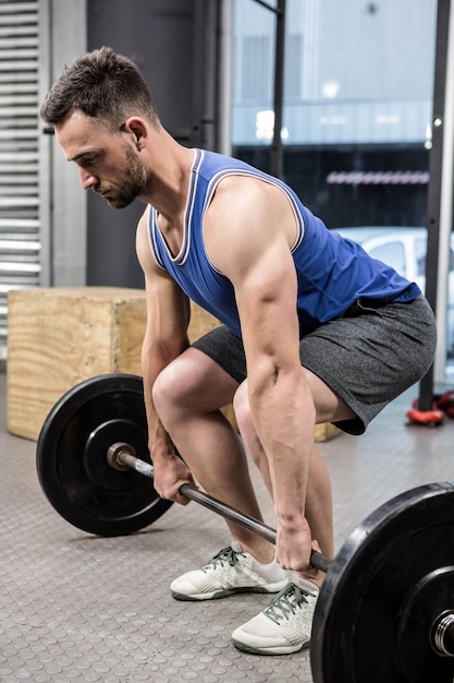 Muscular man lifting barbell at the gym